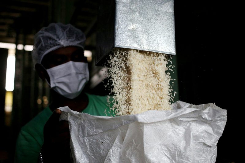 A worker at a mill filling a large sack with freshly milled grain